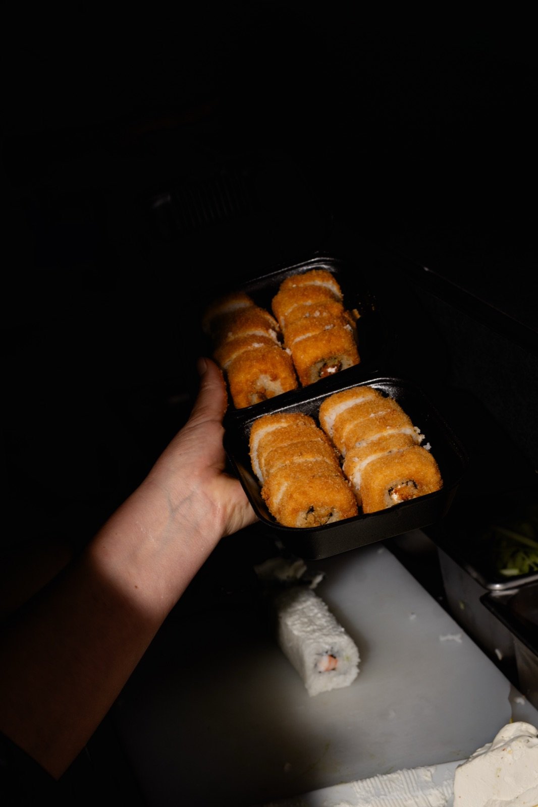 Dos charolas negras de rolls 6shi sobre fondo oscuro
